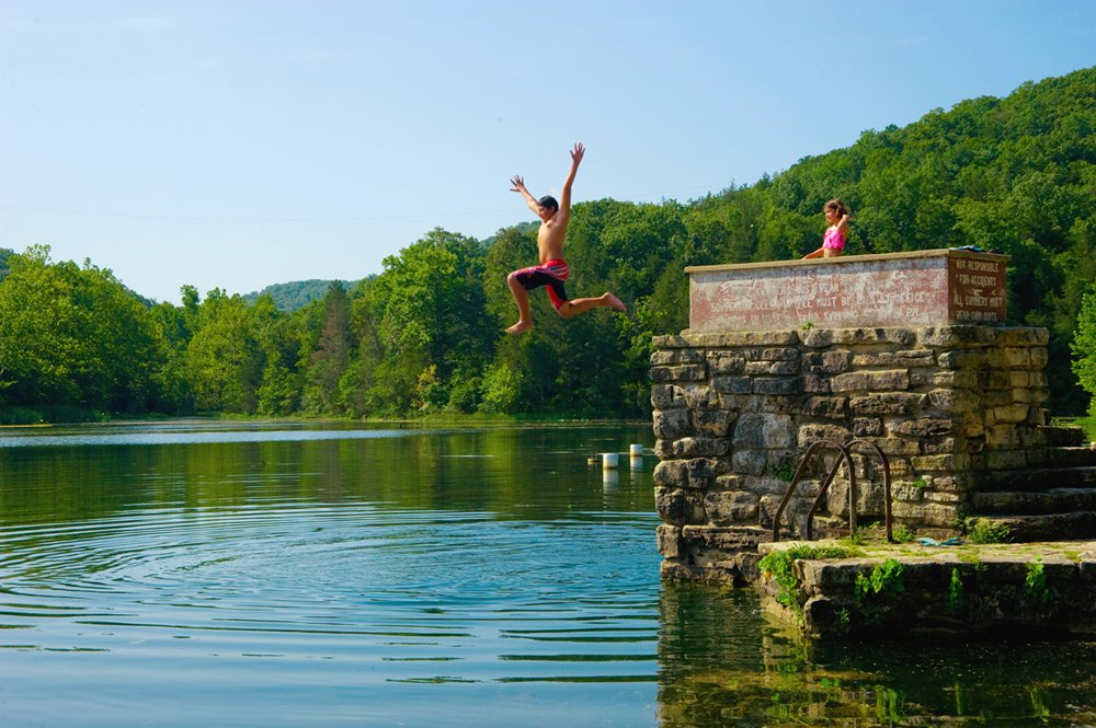 A must-visit thing to do, kids having fun swimming in Lake Leatherwood State Park on a sunny day.