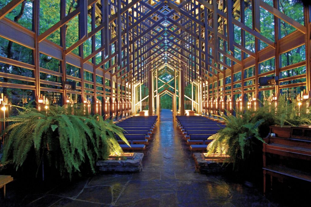 The Thorncrown Chapel, one of the best places to visit in Eureka Springs, illuminated with lights during dusk.